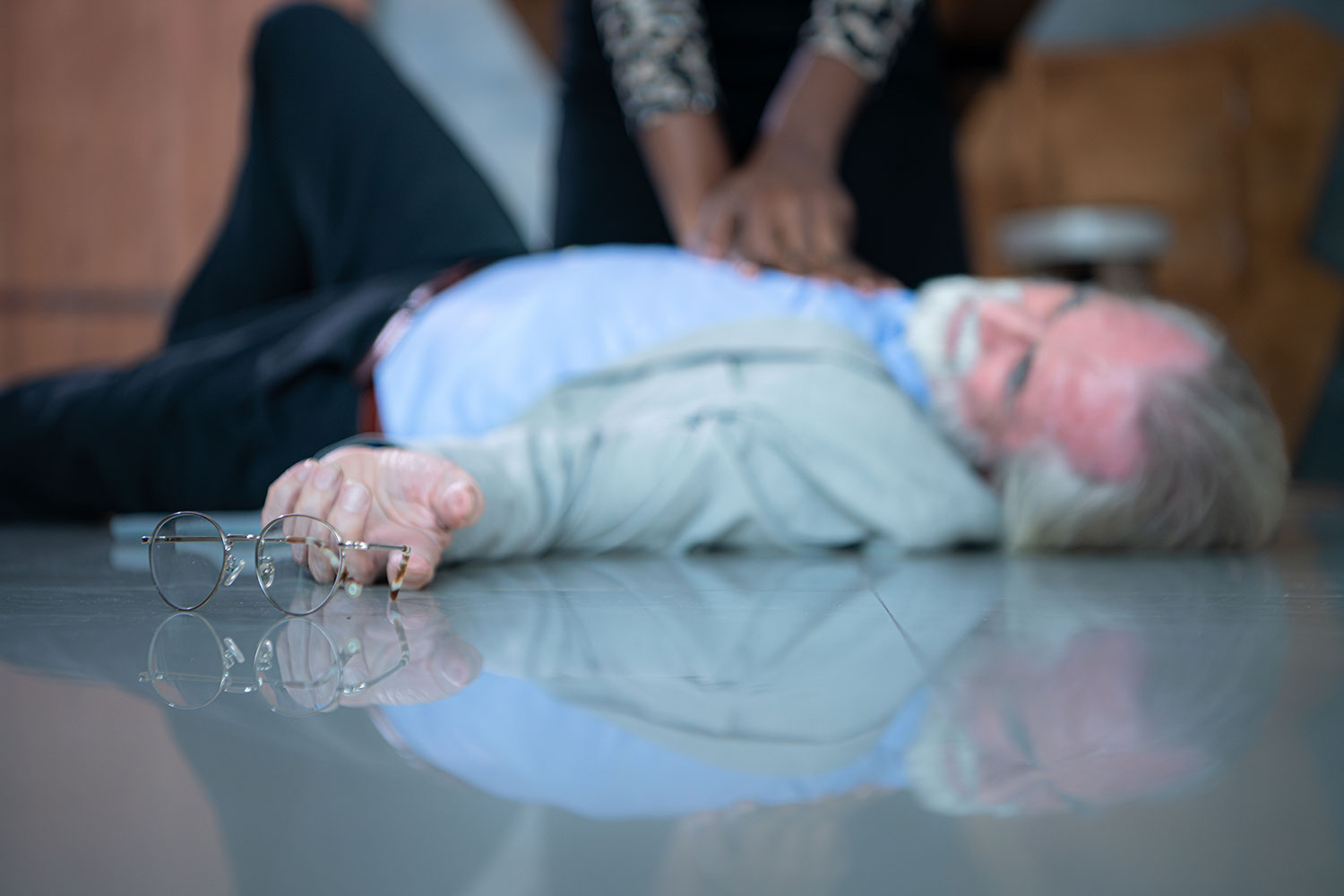 Photo of man unconscious on the floor with CPR being performed